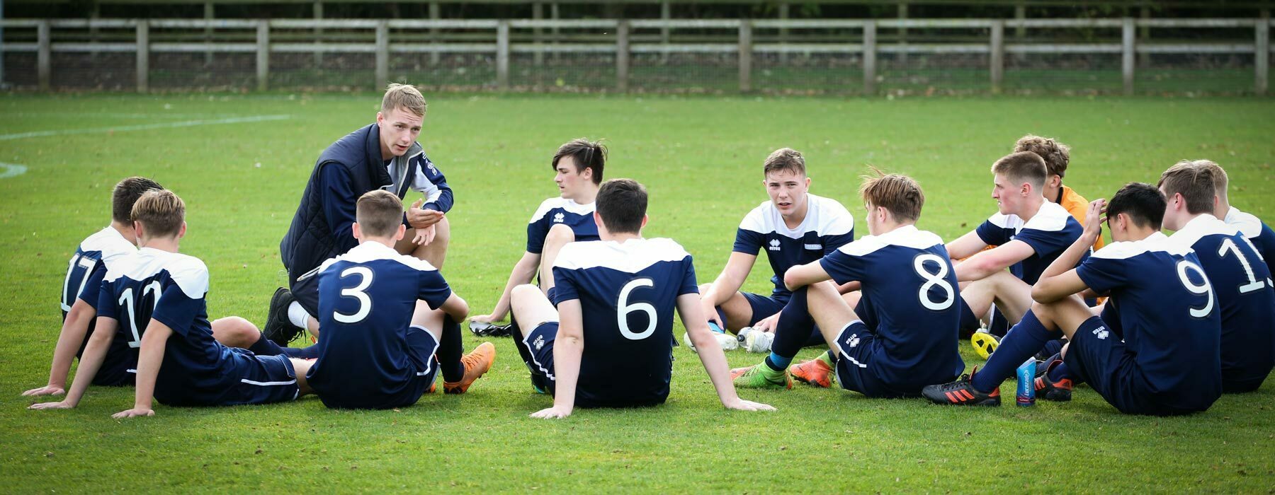 Football academy players on pitch with coach