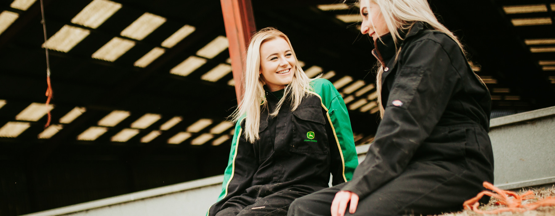 Students on agriculture course sat on hay bales smiling